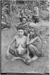 Pregnant woman, face and body smeared with clay (sign of mourning), sits with sister-in-law