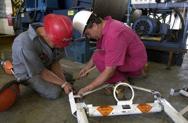 Onboard the Smit-Oceaneering Cable Ship "OCEAN HERCULES", two technicians prepare a small shaped explosive charge during salvage operation, for the Ehime Maru