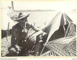 SARANG, NEW GUINEA. 1944-05-25. NX125639 PRIVATE A.C. SOUTH (1), 35TH INFANTRY BATTALION, CLEANING HIS TEETH BESIDE A "DOOVER" (SHELTER) NEAR THE SHORE LINE