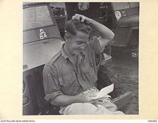 CAPE WOM, WEWAK AREA, NEW GUINEA. 1945-09-06. DRIVER C.J. SPENCE, 6 DIVISION POSTAL UNIT, READING HIS MAIL