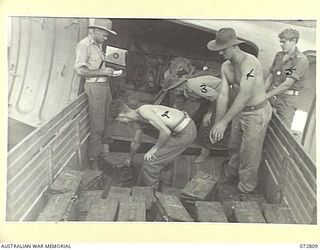 NADZAB, NEW GUINEA, 1944-04-30. AUSTRALIAN TROOPS UNLOAD 25 POUNDER SHELLS FROM A DOUGLAS C47 DAKOTA TRANSPORT AIRCRAFT ON THE AIRFIELD TO A TRUCK. THE AMMUNITION IS BEING TAKEN BY ROAD TRANSPORT ..