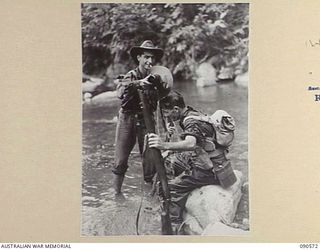 WONGINARA MISSION, NEW GUINEA. 1945-04-08. SIGNALMAN H. HOBSON (1), POURS A HATFUL OF WATER OVER PRIVATE L.W. THWAITES (2). THE MEN, MEMBERS OF 2/3 INFANTRY BATTALION, ARE ENGAGED IN OPERATIONS IN ..