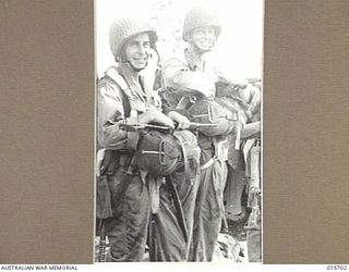 1943-09-15. PARATROOPS LAND AT NADZAB. THREE SMILING AMERICAN PARATROOPERS, CARRYING FULL EQUIPMENT READY TO JOIN ONE OF THE NUMEROUS PLANES WHICH FLEW THEM AND OTHER AMERICAN PARATROOPERS AND ..
