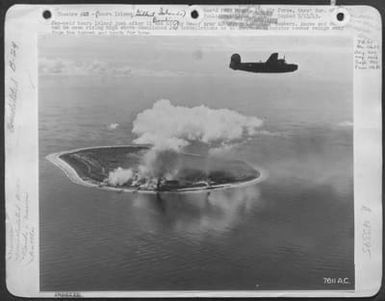 Theater #23. An Army Liberator Views Damaged [Japanese Held] Nauru. Smoke From Two Fires Can Be Seen. Also, Smoke And Dust From Three Hits Near The Phosphate Plants And The Barracks Area Are Seen To The Left Of The Column Of Black Smoke. (U.S. Air Force Number 7611AC)