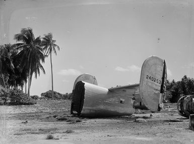 [Tail section of plane lying on ground in Pacific Island setting]