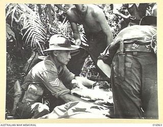 1944-04-17. NEW GUINEA: AN AUSTRALIAN, WOUNDED DURING PATROL DUTY, IS ATTENDED TO BY A FIELD DOCTOR AND A.M.C. PERSONNEL, SOMEWHERE IN THE FINISTERRE RANGES, PREPARATORY TO BEING TRANSPORTED BY ..