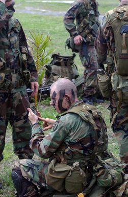 US Army (USA) Soldiers from the 2nd Battalion, 27th Infantry Regiment (2/27) Charlie Company, 25th Infantry Division (ID) [Light], Schofield Barracks, Hawaii (HI), apply camouflage before being picked as part of an Airborne Insert on an island during Exercise TANDEM THRUST 2003