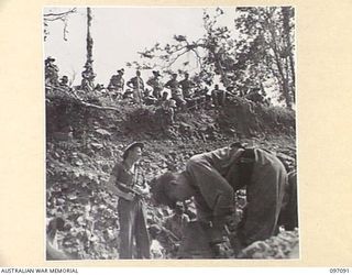 MOUNT SHIBURANGU, WEWAK AREA, NEW GUINEA. 1945-09-21. TROOPS OF HEADQUARTERS 6 DIVISION PERCHED ON A HIGH EMBANKMENT WATCHING TROOPS OF 18 JAPANESE ARMY AT A CONTROLLING POINT AT MAKOW ON THE TOP ..