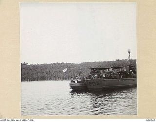 KAIRIRU ISLAND, NEW GUINEA, 1945-09-09. A NAVAL RATING HOISTS THE WHITE ENSIGN ON A JAPANESE BARGE. A PRIZE CREW TOOK CHARGE OF THIS BARGE ON THE ISLAND, WHICH IS NOW UNDER THE CONTROL OF HQ 6 ..