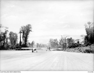 TOROKINA, BOUGAINVILLE ISLAND, SOLOMON ISLANDS. 1945-02-18. TAXIING ALONG THE RUNWAY OF PIVA AIRFIELD AN AUSTER AIRCRAFT OF NO. 17 AIR OBSERVATION POST FLIGHT RAAF FOLLOWS A MUCH LARGER ROYAL NEW ..