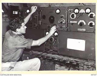 CAPE WOM, NEW GUINEA. 1945-09-29. SIGNALMAN A.W. FRANKE, INSTRUMENT MECHANIC AT RADIO 6 DIVISION, HEADQUARTERS 6 DIVISION. HE IS TUNING THE TRANSMITTER, AND MAKING FINER ADJUSTMENT TO THE FREQUENCY ..