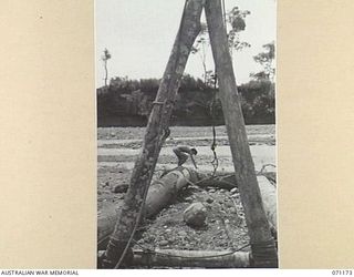 EVAPIA RIVER, NEW GUINEA, 1944-03-15. A MEMBER OF THE 2/4TH FIELD COMPANY, ROYAL AUSTRALIAN ENGINEERS, RIGGING GEAR AND TACKLE TO ERECT THE LARGE MAIN SUPPORT FOR THE SUSPENSION BRIDGE ACROSS THE ..