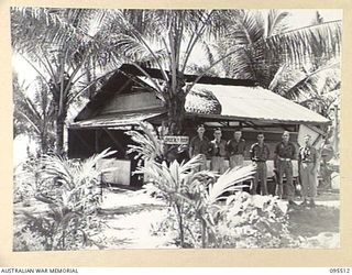 WUNUNG PLANTATION, JACQUINOT BAY, NEW BRITAIN, 1945-08-24. STAFF OF 55 FIELD PARK COMPANY, ROYAL AUSTRALIAN ENGINEERS, OUTSIDE THE ORDERLY ROOM. IDENTIFIED PERSONNEL ARE:- LANCE-CORPORAL N. PROWSE ..