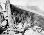 Three soldiers in lean-to shelter, Guadalcanal, 1942