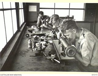 PORT MORESBY, NEW GUINEA. 1944-04-10. QX47436 CRAFTSMAN H.E. BROWN, WITH VX71246 CRAFTSMAN A.T. HUTCHINSON, AND VX86395 CORPORAL L.C. ARTHUR, WORKING IN THE INSTRUMENT REPAIR SECTION AT THE 1ST ..