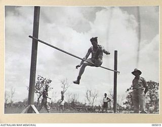 HERBERTON, QLD. 1945-01-19. PRIVATE RYAN, HQ 26 INFANTRY BRIGADE, (1), KNOCKING THE BAR AT 5 FEET 5 INCHES IN THE HIGH JUMP EVENT DURING THE 9 DIVISION GYMKHANA AND RACE MEETING HELD AT HERBERTON ..