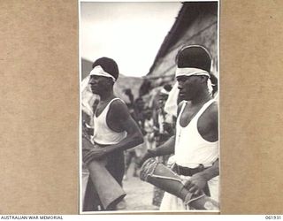 KILA KILA, PAPUA, NEW GUINEA. 1943-12-25. KEREMA BOYS EXECUTING A DANCE AT THE AUSTRALIAN AND NEW GUINEA ADMINISTRATION UNIT NATIVE LABOUR CAMP. THE DANCERS WEAR LONG TRAILS OF GRASS AND FLOWERS, ..