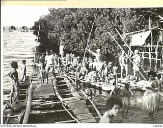 PAPUA, NEW GUINEA. 1942-07. AN AUSTRALIAN INFANTRY PARTY LEAVING A NATIVE VILLAGE ENCOUNTERED WHILE ON PATROL. THEY ARE ABOARD A "LAKATOI" MANNED BY FIVE SMALL BOYS, BUT THE DIGGERS LENT A HAND AND ..
