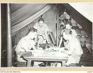 MILNE BAY, PAPUA. 1942-09. AUSTRALIAN FIGHTER PILOTS PLAY DRAUGHTS WHILE WAITING FOR ALARM CALLS. LEFT TO RIGHT: FLYING OFFICER P.B. JONES; FLIGHT SERGEANT R.W. CRAWFORD; PILOT OFFICER N.C. TODD; ..