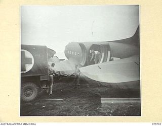 DREGER HARBOUR, NEW GUINEA. 1944-01. MEMBERS OF THE 10TH FIELD AMBULANCE, AUSTRALIAN ARMY MEDICAL CORPS, LOAD STRETCHER CASES ABOARD A UNITED STATES ARMY AIR FORCE TRANSPORT AIRCRAFT