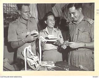 LAE AREA, NEW GUINEA. 1945-06-03. CAPTAIN A.J. MARSHALL, 2/5 INFANTRY BATTALION (1) WITH SENIOR SISTER H.M. MCBEAN, RAAF AIR EVACUATION TRANSPORT UNIT (2) AND LIEUTENANT F. FOOKE, 18 HEAVY WIRELESS ..