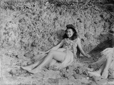 [Portrait of a Polynesian woman reclining on coastal rocks]