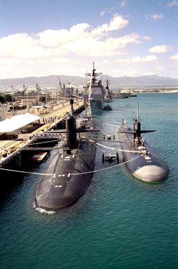 The nuclear-powered strategic missile submarine USS ALABAMA (SSBN-731), left, and the nuclear-powered attack submarine USS SAN FRANCISCO (SSN-711) are moored together at a pier in front of the guided missile cruiser USS CHOSIN (CG-65) during the change of command ceremony for the commander, U.S. Pacific Fleet