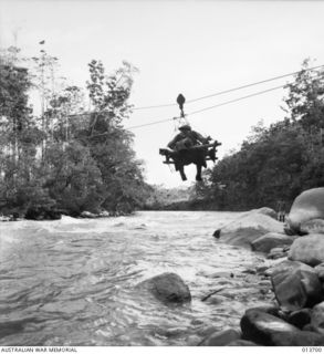 1942-12-01. NEW GUINEA. KANUSI RIVER. AUSTRALIAN TROOPS CROSS THE KANUSI RIVER ON FLYING FOXES HASTILY CONSTRUCTED BY ENGINEERS. (NEGATIVE BY G. SILK)
