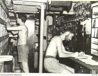 AT SEA. 1944-08/09. RATINGS WORKING IN THE NAVAL STORE ABOARD THE RAN CORVETTE, GEELONG AS THE VESSEL PROCEEDS ALONG THE NEW GUINEA COAST
