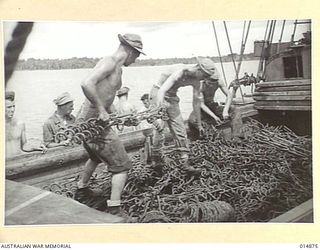 1943-05-19. NEW GUINEA. GONA. ALLIED TROOPS UNLOADING BARBED WIRE AND STEEL PICKETS ON TO A PONTOON FERRY AT GONA. (NEGATIVE BY N. BROWN)