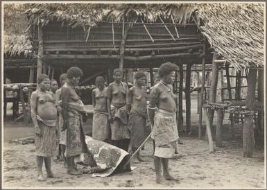 Funeral ceremony, Wanigella [Wanigela], [group of women standing by a body covered by cloth] Frank Hurley