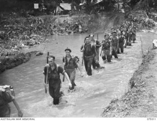 BOUGAINVILLE ISLAND. 1945-03-01. PERSONNEL OF THE 61ST INFANTRY BATTALION WADING THROUGH A SECTION OF THE MOSIGETTA RIVER WHICH HAS BEEN FLOODED BY THE OVERFLOWING HUPAI RIVER. FOR IDENTIFICATION ..