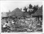 More than 100 native Samoans sitting on the ground in their village during a feast of roast pigs in Samoa, ca.1900