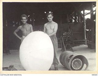 TOKO AREA, SOUTH BOUGAINVILLE. 1945-08-27. CORPORAL H.L. BOYD (1) AND STAFF SERGEANT BEAGLEY (2) MEMBERS OF 126 BRIGADE WORKSHOP, WITH A LIGHT REFLECTOR THEY MADE FOR THE OPERATING THEATRE, 106 ..