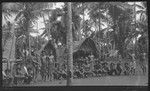 Group in a village, men on left hold cricket bats