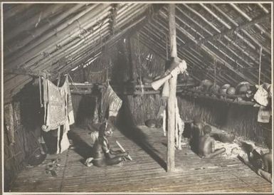 Scenes around Wanigella [Wanigela], [interior of a hut with a man and children sitting on the floor] Frank Hurley