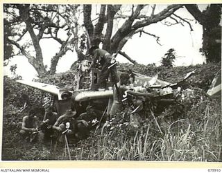 DAGUA, NEW GUINEA. 1945-03-25. PERSONNEL OF THE 2/2 INFANTRY BATTALION ALONGSIDE THE WRECKAGE OF A JAPANESE ZERO. NOTE THE "DOOVER" (SHELTER), CONSTRUCTED UNDER THE WING. IDENTIFIED PERSONNEL ARE:- ..