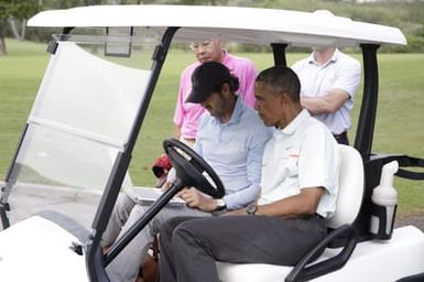 Barack Obama confers with Robert Baker after he plays golf in Kaneohe Bay, Hawaii, December 24, 2014