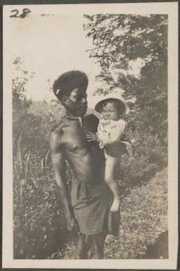 Solomon Island man holding a Japanese baby, New Britain Island, Papua New Guinea, probably 1916