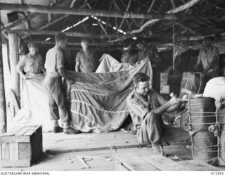 NADZAB, NEW GUINEA. 1944-05-21. MEMBERS OF THE 3RD AIR MAINTENANCE COMPANY PACKING SUPPLIES TO BE DROPPED BY PARACHUTE TO TROOPS IN FORWARD AREA. A "POL" (PETROL, OIL, AND LUBRICANT), PACK WITH ..