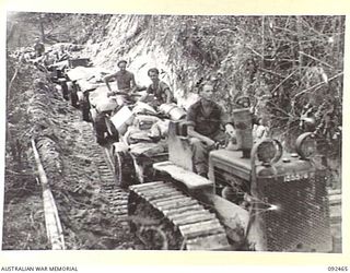 BOUGAINVILLE. 1945-05-22. A B SQUADRON, 2/4 ARMOURED REGIMENT TRACTOR TOWING A JEEP TRAIN THROUGH A CUTTING IN EGAN'S RIDGE, CARRYING FRESH FOOD AND SUPPLIES TO FORWARD TROOPS IN THE POROREI RIVER ..