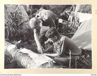 BOUGAINVILLE. 1945-05-24. CAPTAIN K.R.G. COLEMAN, OFFICER COMMANDING D COMPANY, 26 INFANTRY BATTALION (AUSTRALIAN IMPERIAL FORCE) (1), SHAVES WHILE PRIVATE J.B. CRACE (2), SHOWS HIM REPORTS OF THE ..
