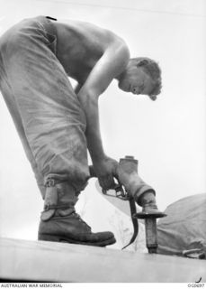 NADZAB, NEW GUINEA. C. 1944-02. BARE TO THE WAIST, LEADING AIRCRAFTMAN D. W. COLLIS, CHESTER HILL, NSW, REFUELLING A VULTEE VENGEANCE DIVE BOMBER AIRCRAFT OF NO. 24 SQUADRON RAAF