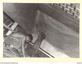 TOROKINA, BOUGAINVILLE. 1945-05-31. SAPPER UTTING (1) AND SAPPER F. THOMPSON (2), MEMBERS OF 10 FIELD COMPANY ROYAL AUSTRALIAN ENGINEERS, LINING THE TOP OF WALLS AND CEILING WITH SISALCRAFT IN ..