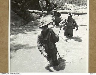 FARIA RIVER, RAMU VALLEY, NEW GUINEA. 1944-01-18. NX136443 GUNNER R. FOLEY OF NO. 7 BATTERY, 2/4TH FIELD REGIMENT FORDING THE FAST FLOWING FARIA RIVER ON HIS WAY TO THE FORWARD POSITIONS