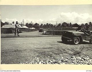 LAE, NEW GUINEA, 1944-03-27. VX135979 CORPORAL M. H. SYKES (LEFT), 3RD DIVISION PROVOST COMPANY, ATTACHED TO LAE BASE SUB-AREA, ON TRAFFICE CONTROL DUTY AT THE CHARING CROSS INTERSECTION