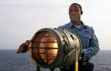 Signalman Third Class (SM3) Young tests a signal light onboard the USS SAIPAN (LHA 2)