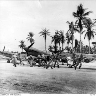 MOMOTE, LOS NEGROS ISLAND, ADMIRALTY ISLANDS. C. 1944-03. ON THE WORD, PILOTS OF NO. 76 (KITTYHAWK) SQUADRON RAAF BREAK AWAY FROM THE BRIEFING AND RACE FOR THEIR AIRCRAFT. MISSION TAKES THEM OFF IN ..