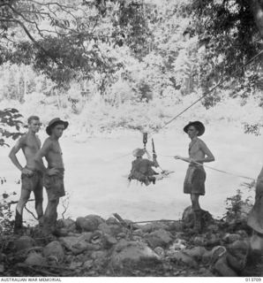 1942-12-01. NEW GUINEA. KANUSI RIVER. AUSTRALIAN TROOPS CROSS KANUSI RIVER ON FLYING HASTILY CONSTRUCTED BY ENGINEERS. (NEGATIVE BY G. SILK)
