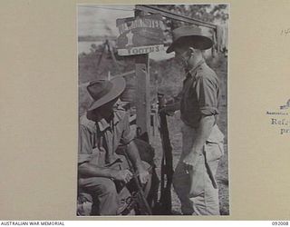 WEWAK POINT, NEW GUINEA, 1945-05-12. L-CPL K.J. GRAHAM (1), AND SGT P.A. CONSTABLE (2), MEMBERS OF 2/4 INFANTRY BATTALION BESIDE A ROADSIDE SIGN AWAITING ORDERS FOR ANOTHER MOVE